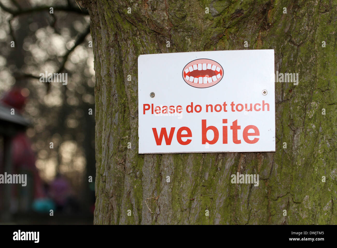 please do not touch feed the animals we bite sign screwed to tree Stock