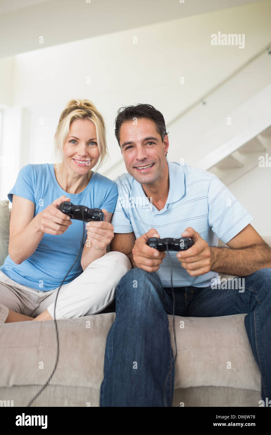 Cheerful couple playing video games in living room Stock Photo - Alamy