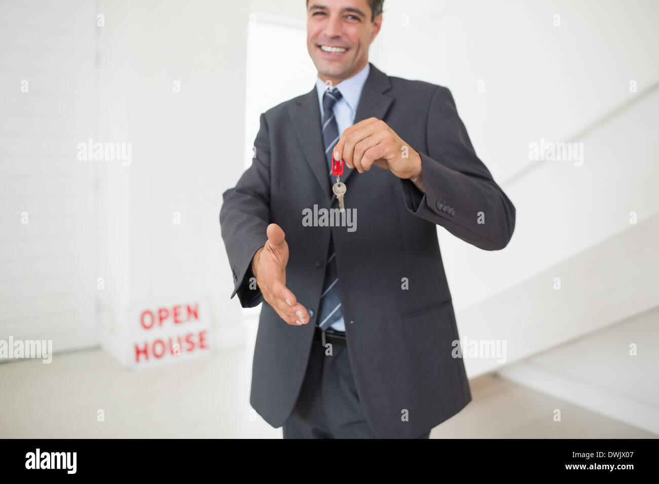Businessman offering a handshake while holding up keys Stock Photo