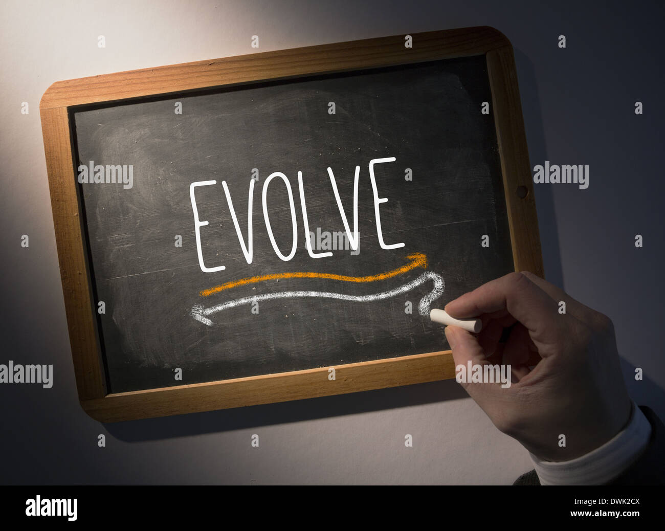 Hand writing Evolve on chalkboard Stock Photo