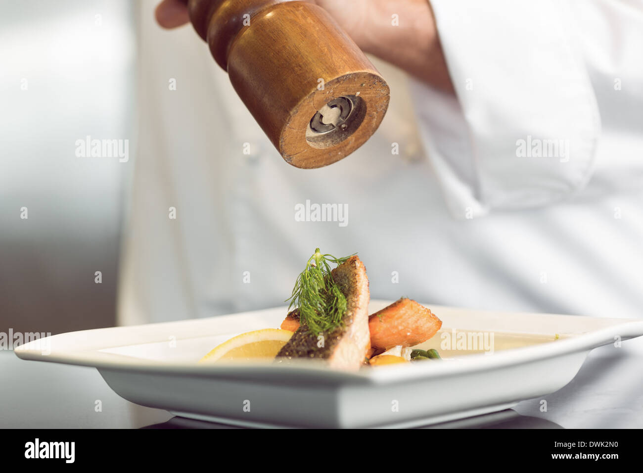 Closeup shot of hands grinding pepper on food Stock Photo