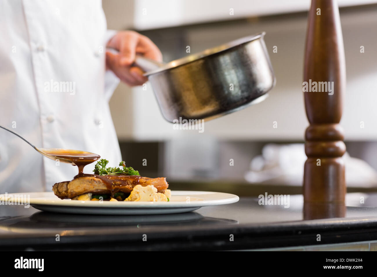 Closeup mid section of a chef garnishing food Stock Photo