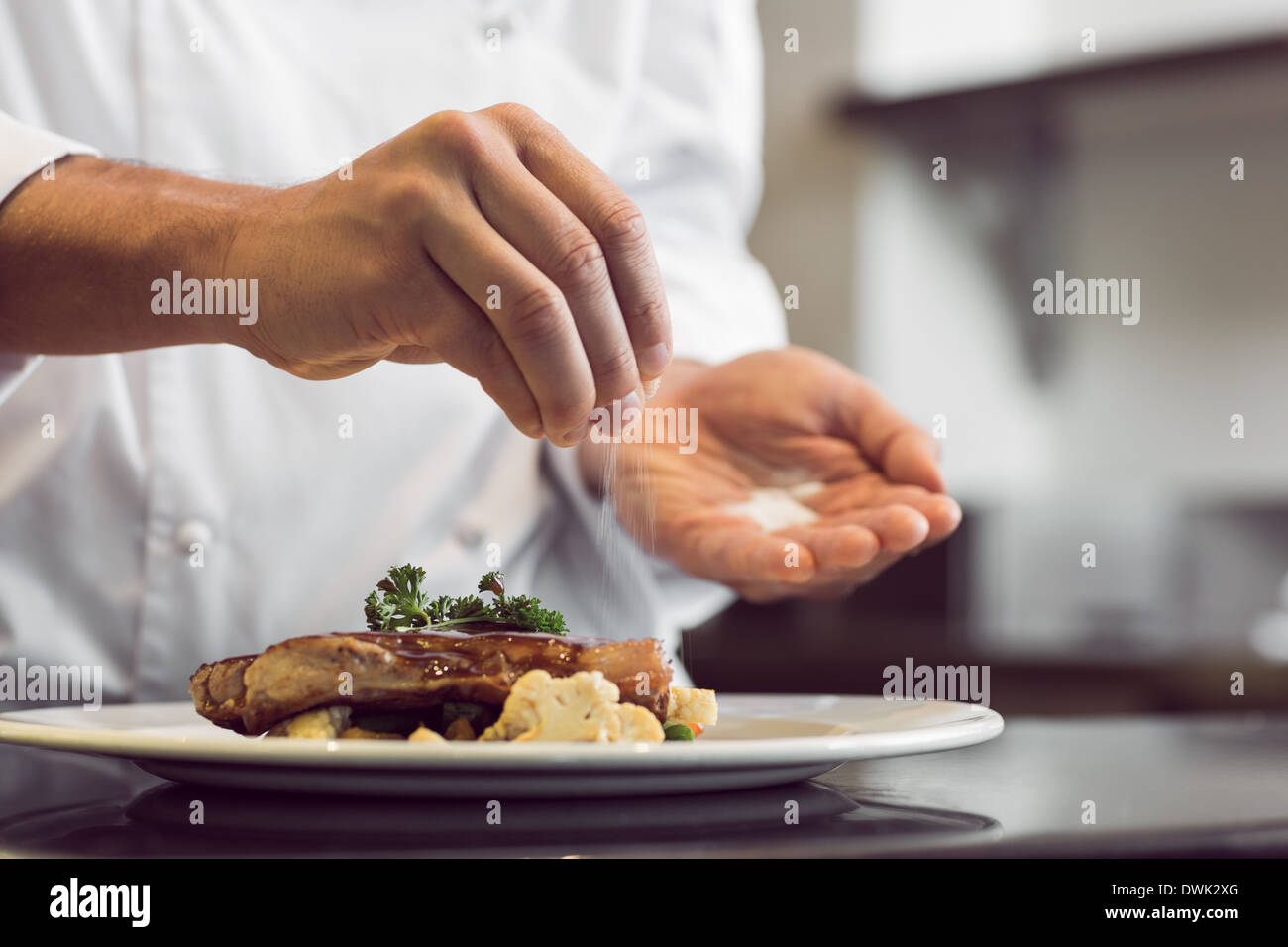 Closeup mid section of a chef putting salt Stock Photo