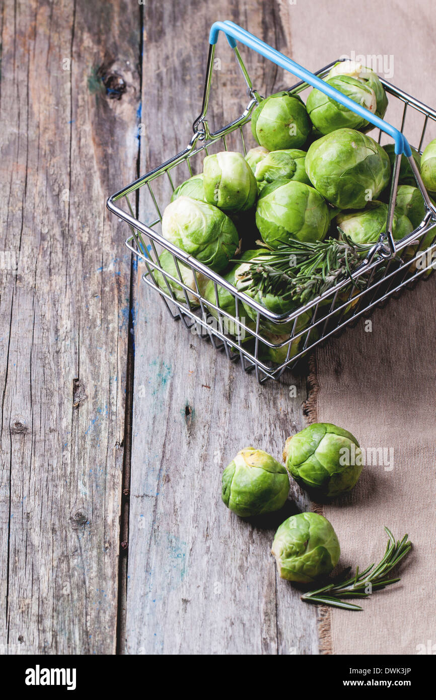 Food basket of brussels sprouts and rosemary on old wooden table. Stock Photo