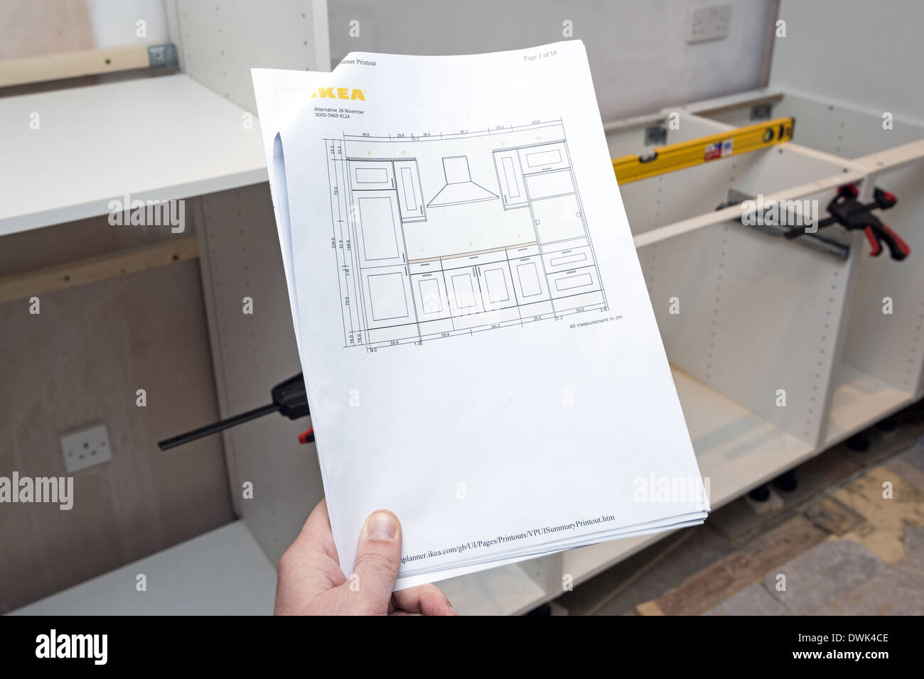 Man holding Ikea kitchen plan with half built kitchen in the background Stock Photo