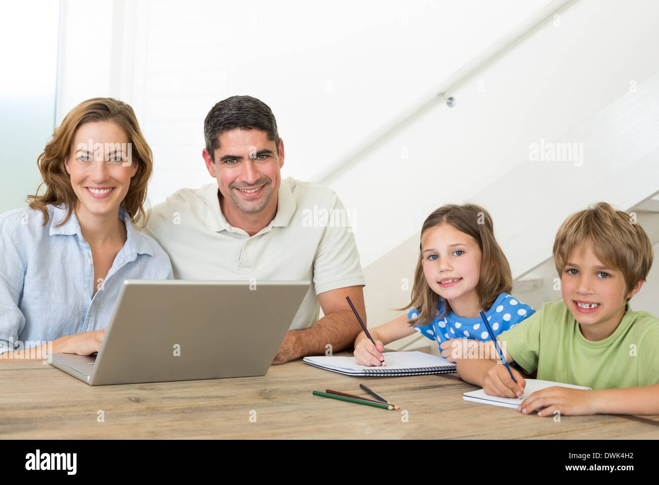 Parents with laptop while children coloring at table Stock Photo