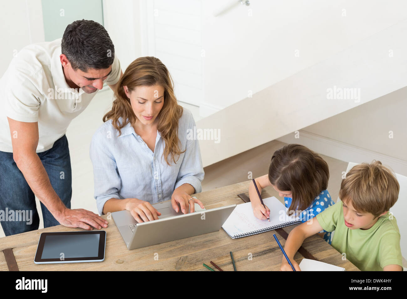 Parents using laptop while children coloring at home Stock Photo