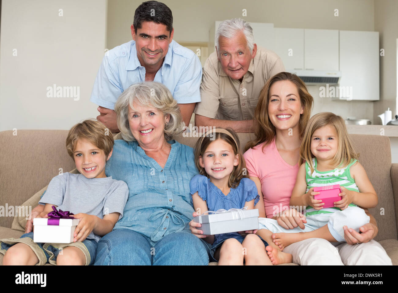 Siblings holding gifts with family in living room Stock Photo