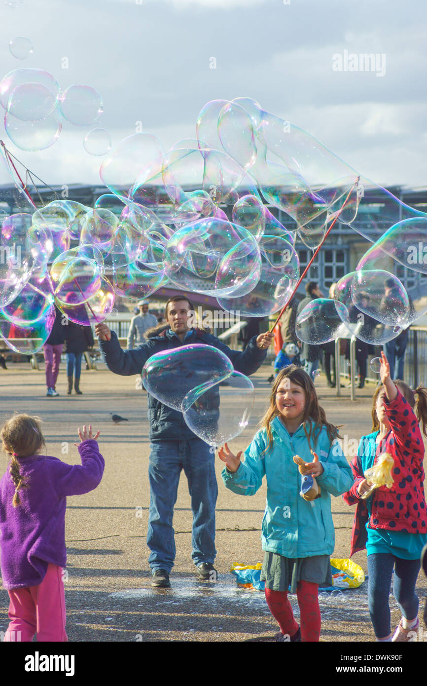 Street entertainer blows bubbles for children  London South bank.  Children playing with bubbles Stock Photo