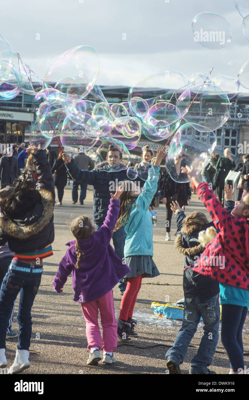 Street entertainer blows bubbles for children  London South bank.  Children playing with bubbles Stock Photo