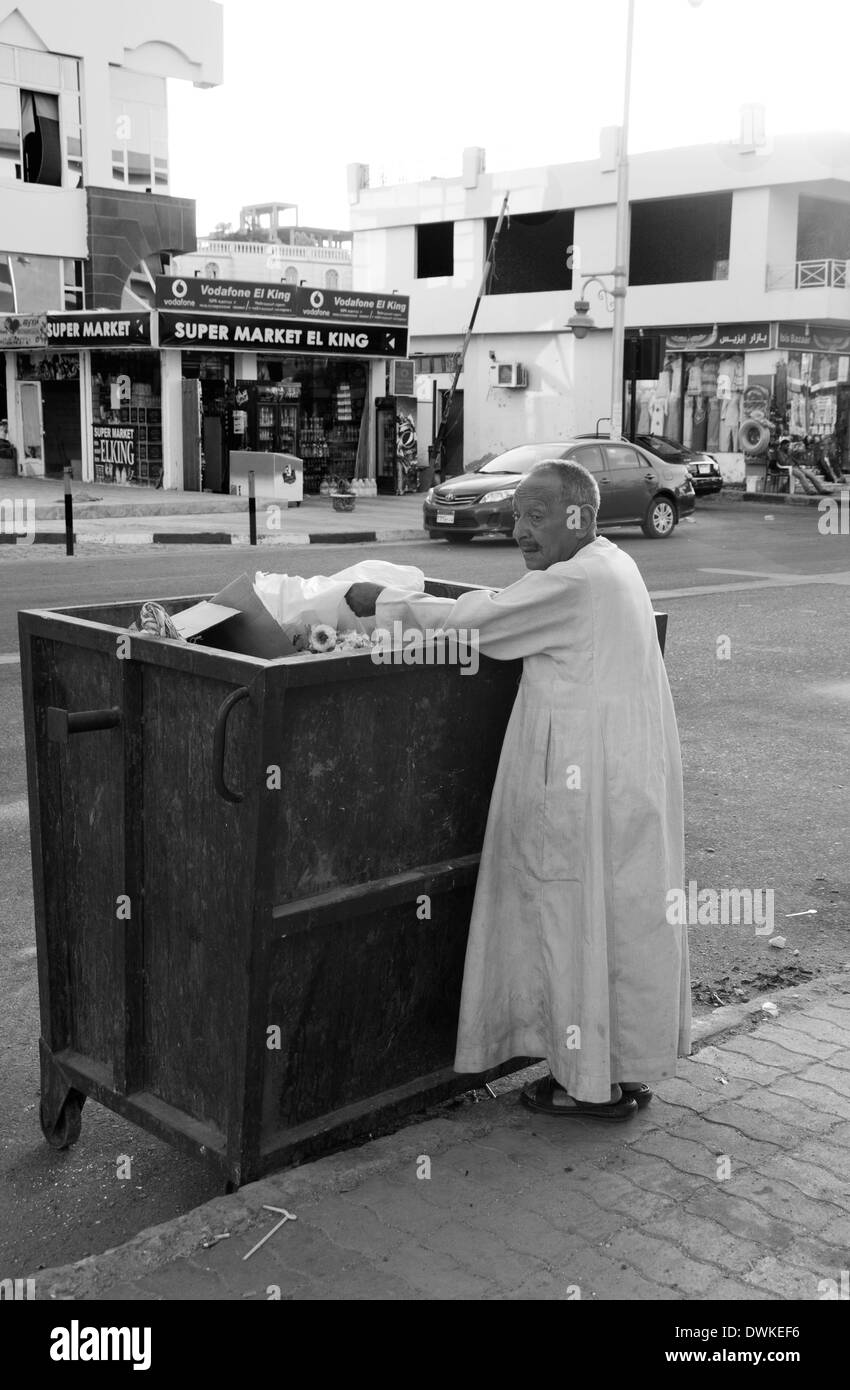 Man looking through a bin on the tourist strip in Hurghada, Egypt Stock Photo