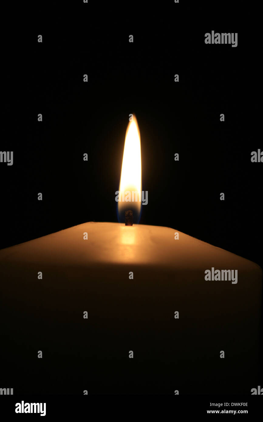 a white burning candle with black background Stock Photo - Alamy