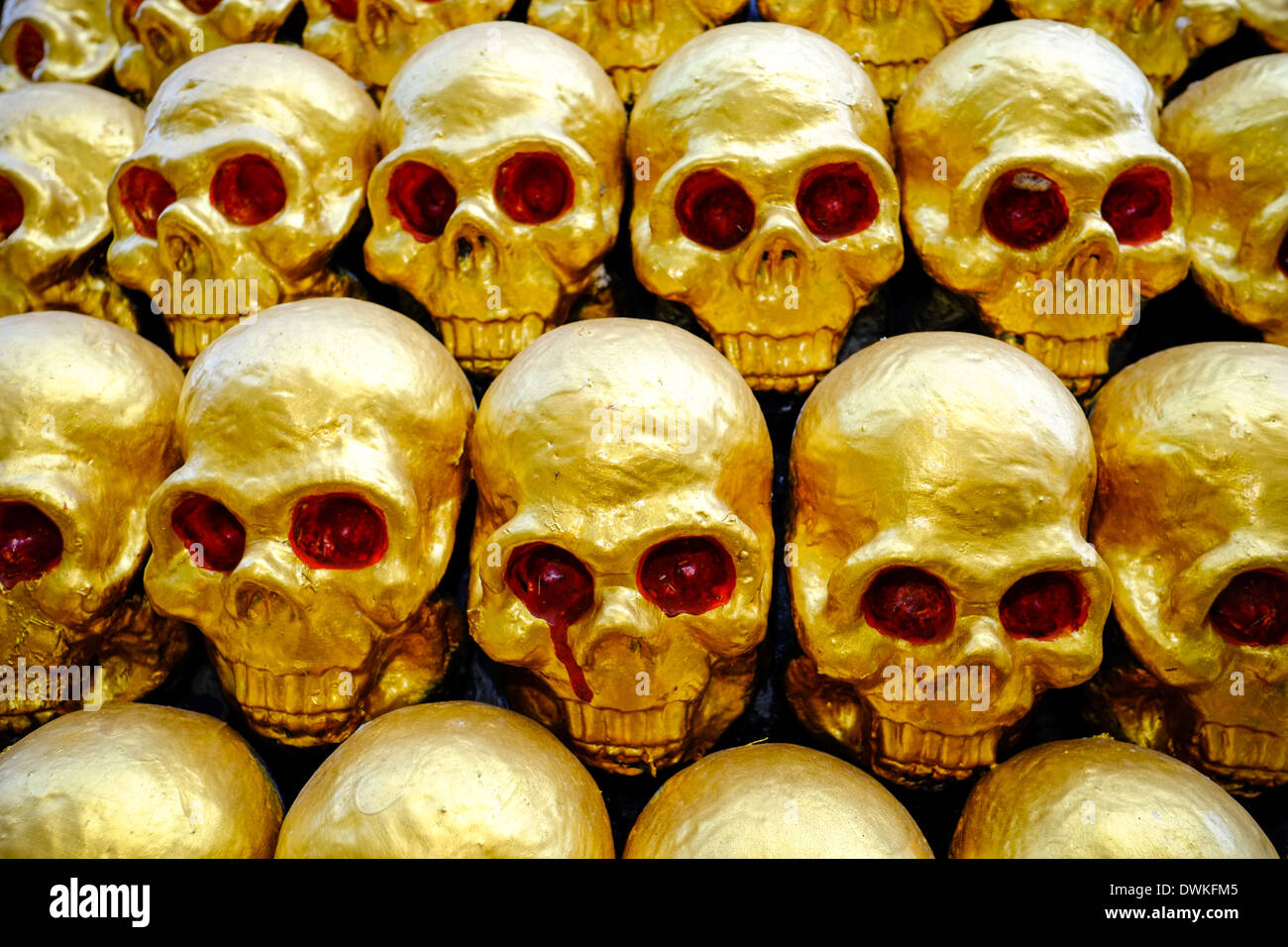 golden skulls with red painted eyes. piled in rows. temple art. Phuket, Thailand Stock Photo