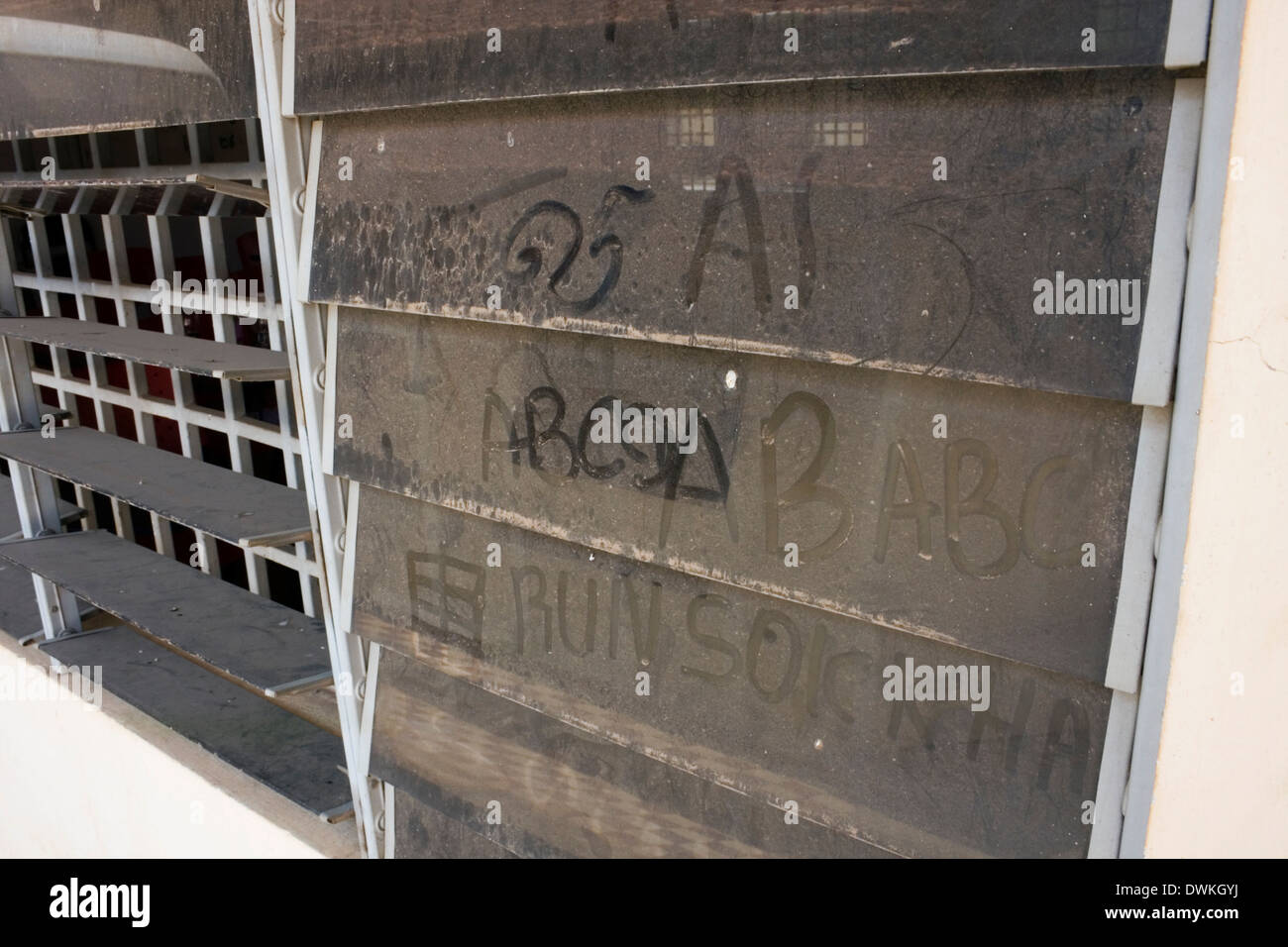 Graffiti is writtten on a dusty and dirty louvered glass window at a classroom Stock Photo