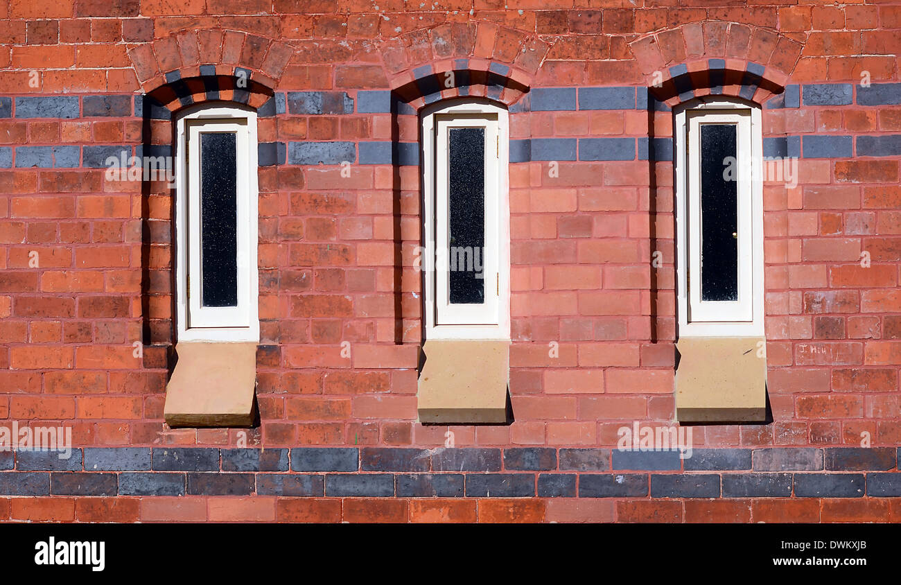 3 Windows vertically set in a brick wall with contrasting bricks horizontally Stock Photo