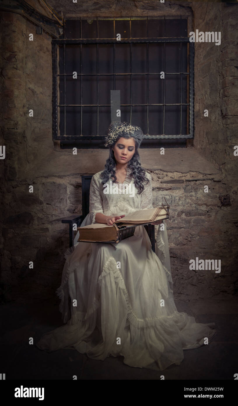 Young woman in white dress reading the old book Stock Photo