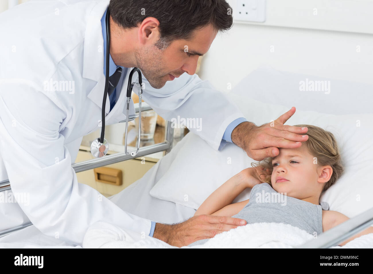 Doctor examining temperature of ill girl Stock Photo