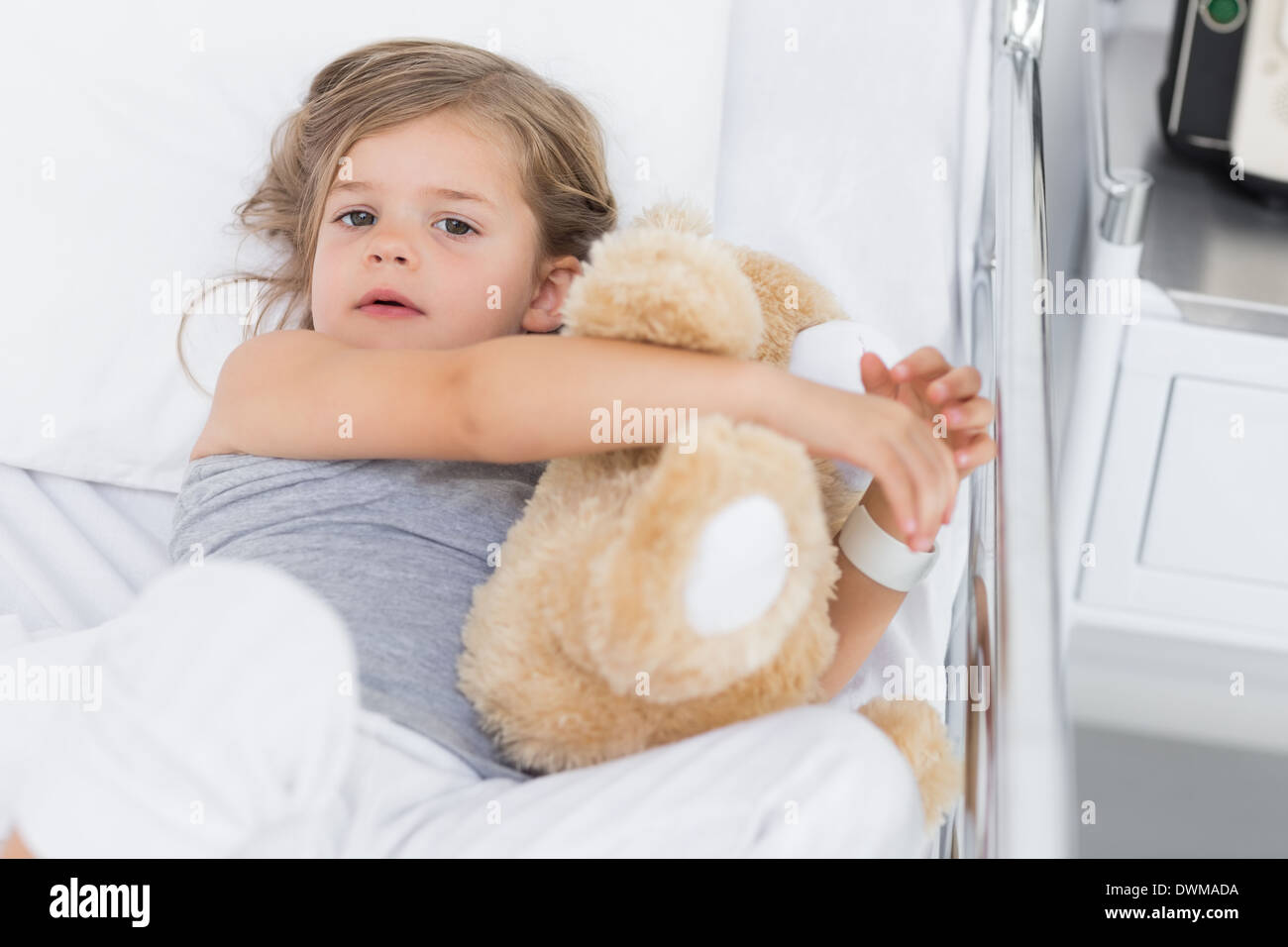 Cute girl hugging teddy bear in hospital bed Stock Photo