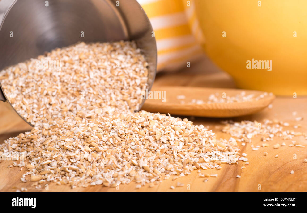 Healthy steelcut whole oats spilling out of a measuring cup Stock Photo