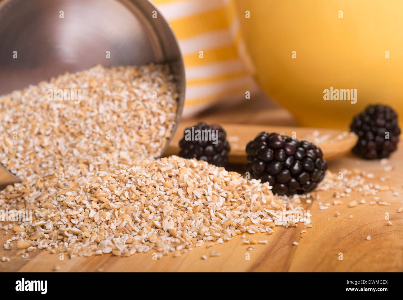 Healthy steelcut whole oats spilling out of a measuring cup with blackberries Stock Photo