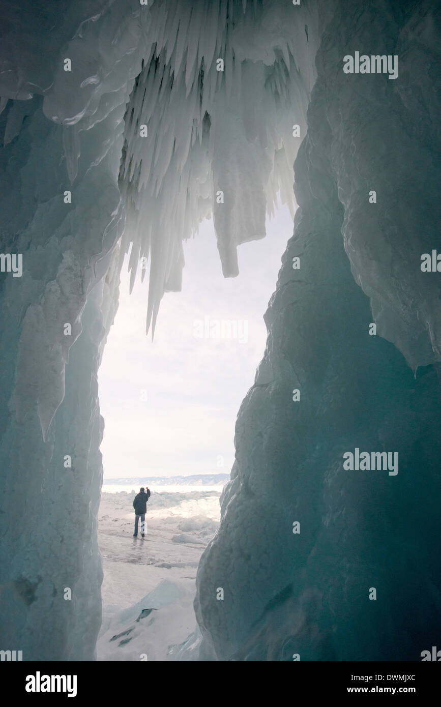 Tourist framed in the frozen mouth of ice cave, Olkhon Island, Lake Baikal, Irkutsk Oblast, Siberia, Russia Stock Photo