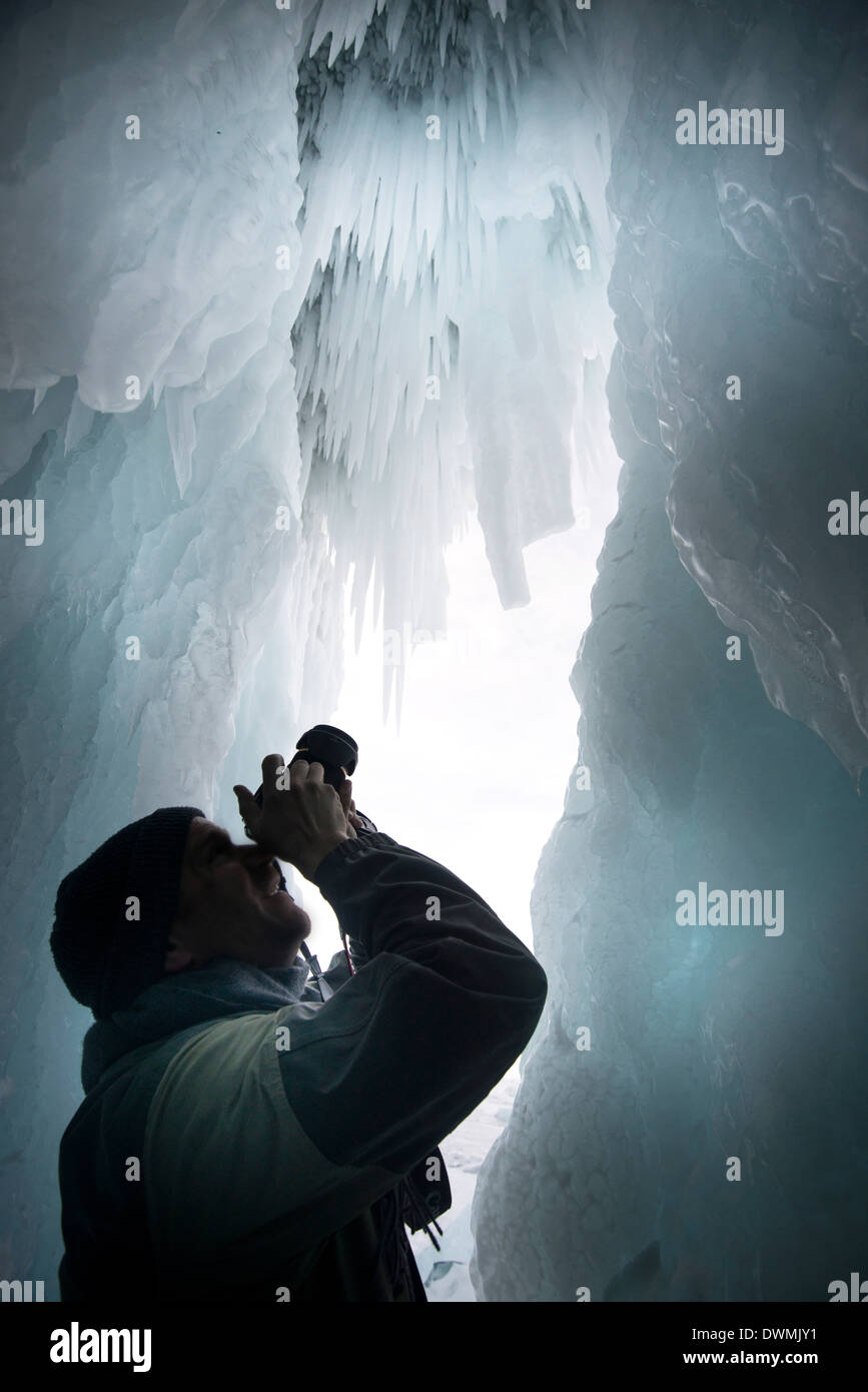 Tourist framed in the frozen mouth of ice cave, Olkhon Island, Lake Baikal, Irkutsk Oblast, Siberia, Russia Stock Photo