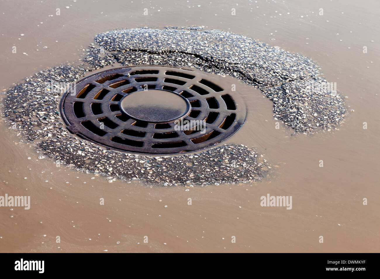 Melted water flows down through the manhole cover on spring day Stock Photo