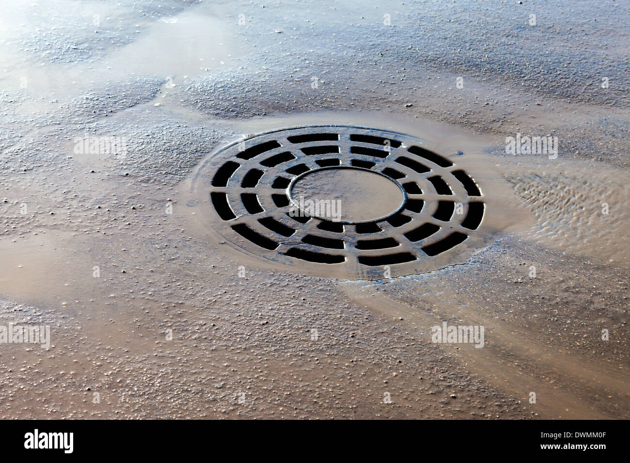 Melted water flows down through the manhole cover on spring day Stock Photo