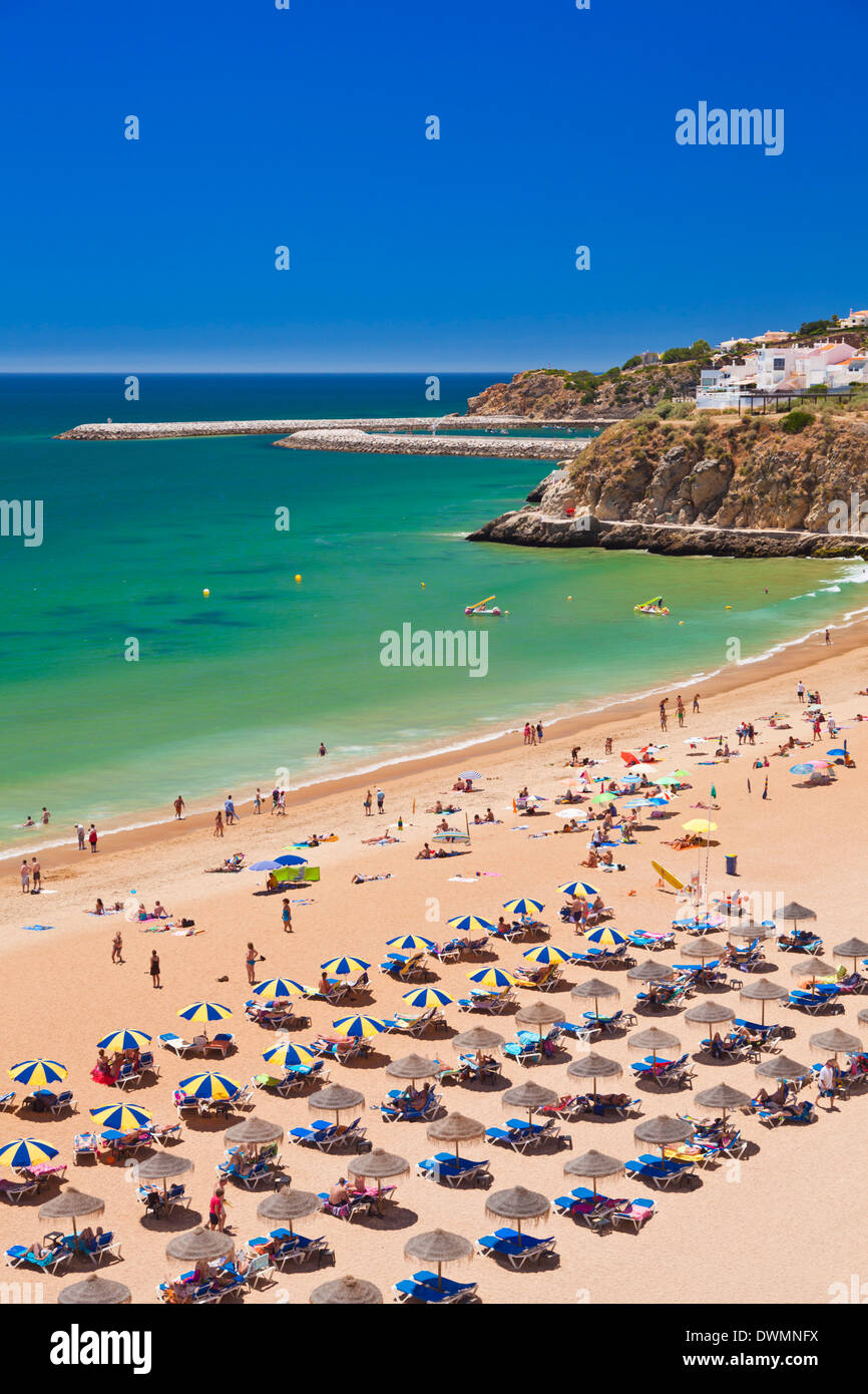 Holidaymakers sunbathing under beach umbrellas on the sandy beach at Praia do Tunel, Albufeira Beach, Algarve, Portugal, Europe Stock Photo