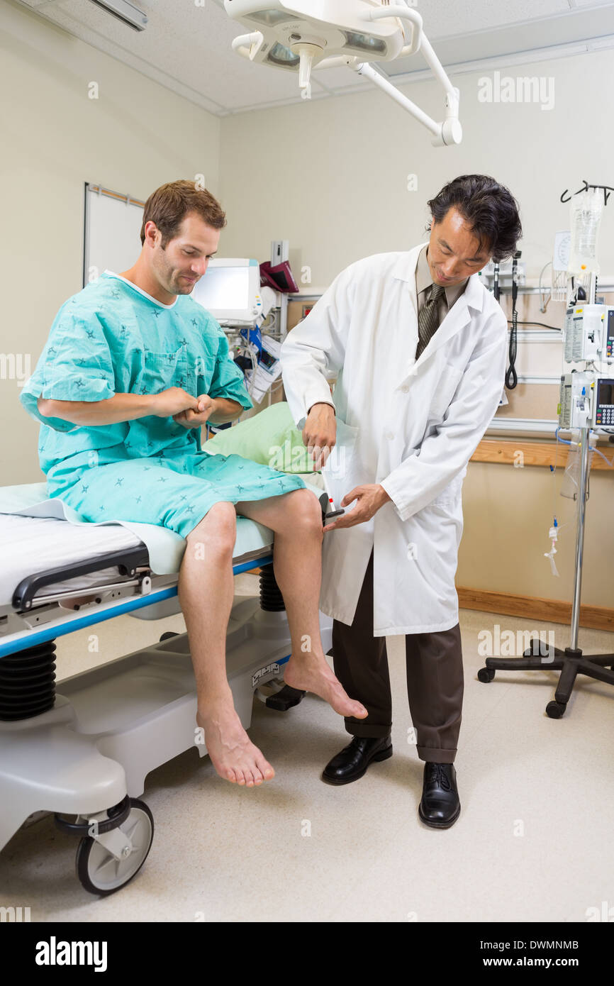 Doctor Examining Patient's Knee With Hammer In Hospital Stock Photo