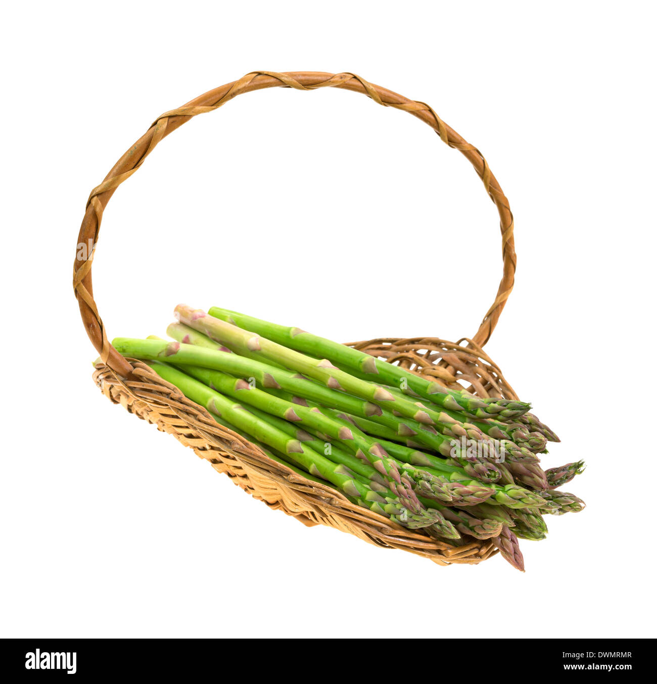 An old wicker basket with fresh asparagus stalks on a white background. Stock Photo