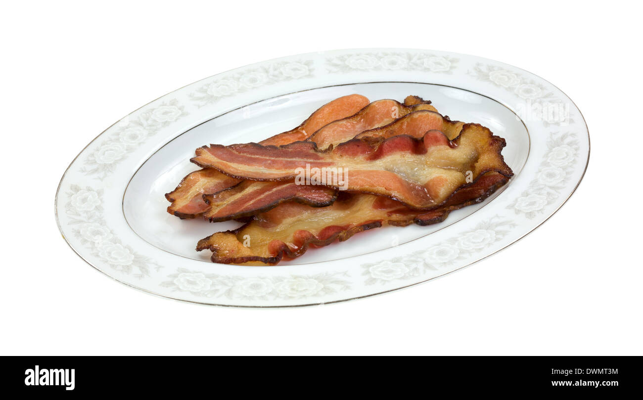 Several slices of freshly cooked smoked thick sliced bacon on an old glass platter. Stock Photo