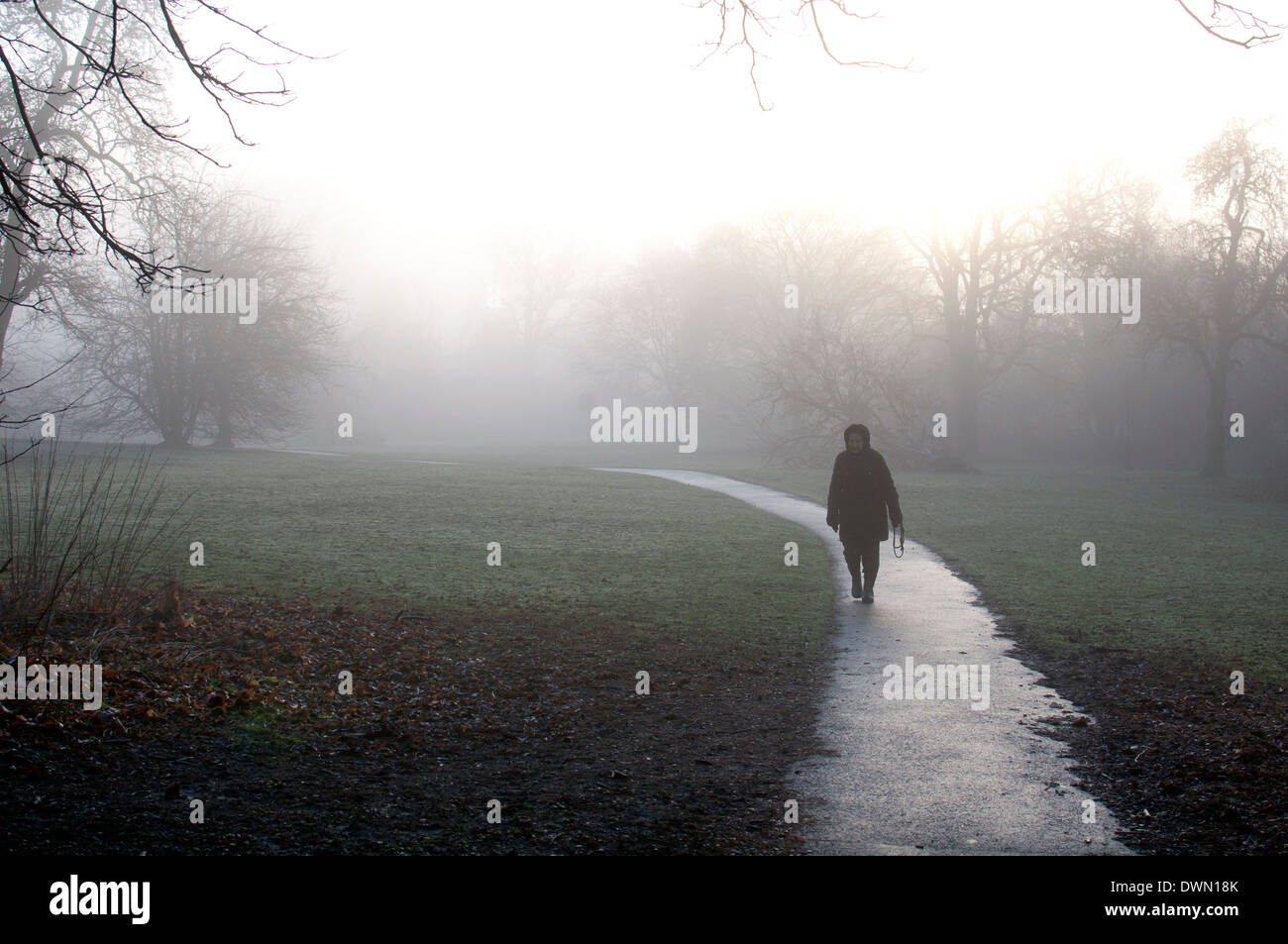 Elderly woman on footpath in foggy weather, Priory Park, Warwick, UK Stock Photo