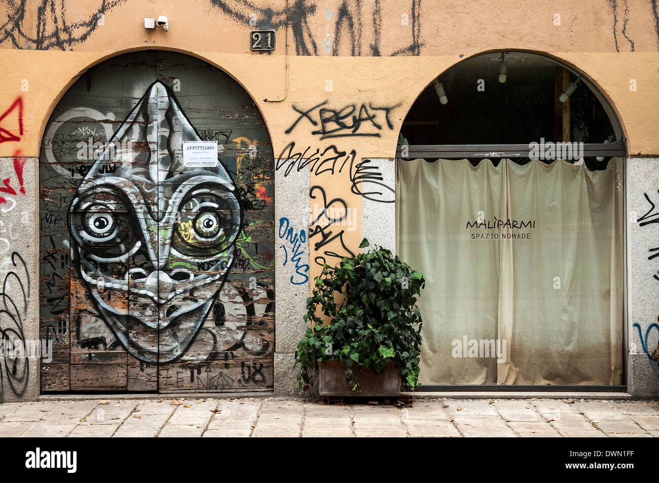 Shop with door decorated by graffiti representing an alien face, Milan, Lombardy, Italy Stock Photo