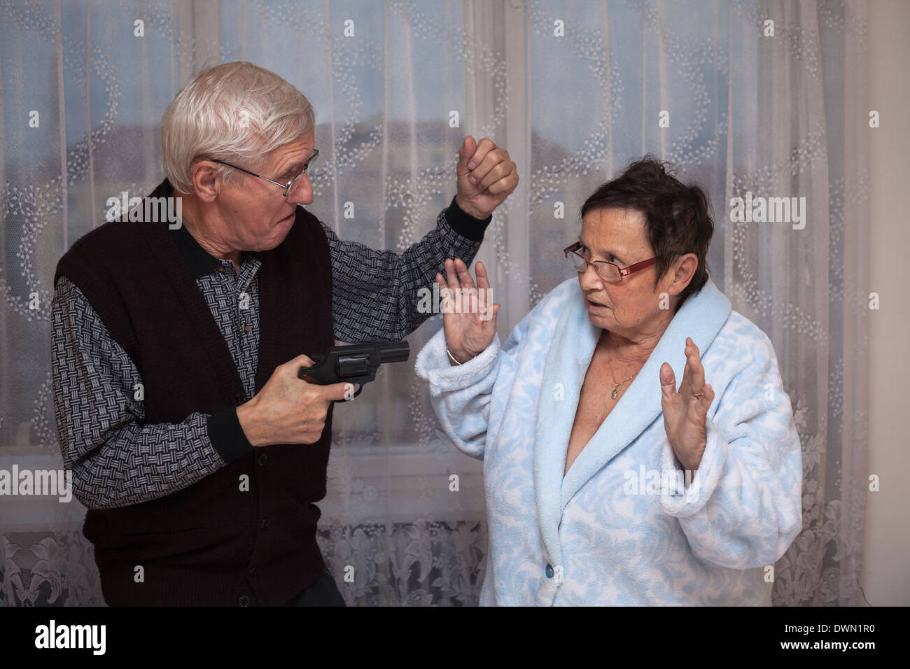 Mad senior couple fighting with a gun. Stock Photo