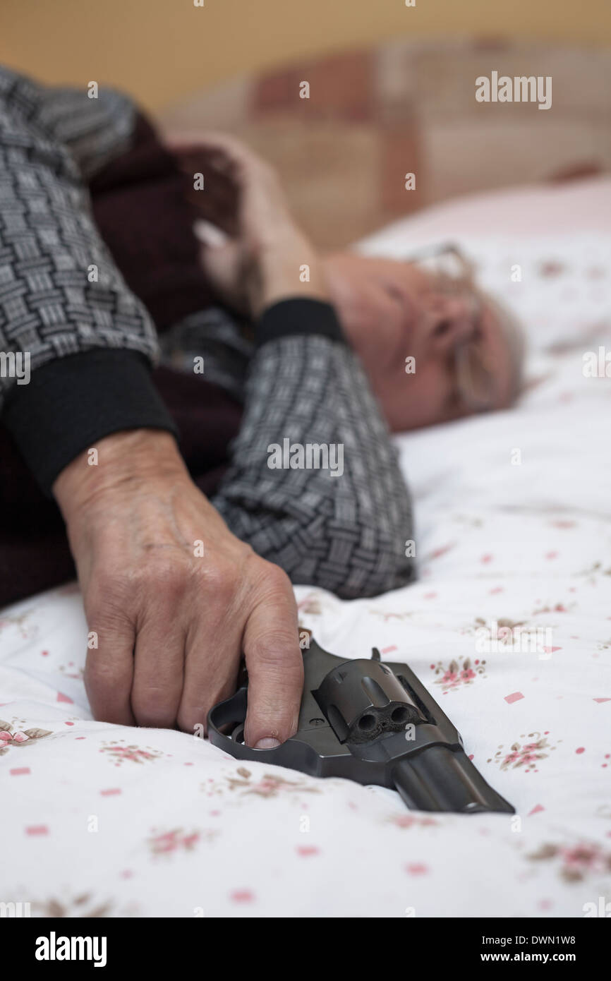 Suicide concept. Closeup of dead senior man holding a gun. Stock Photo