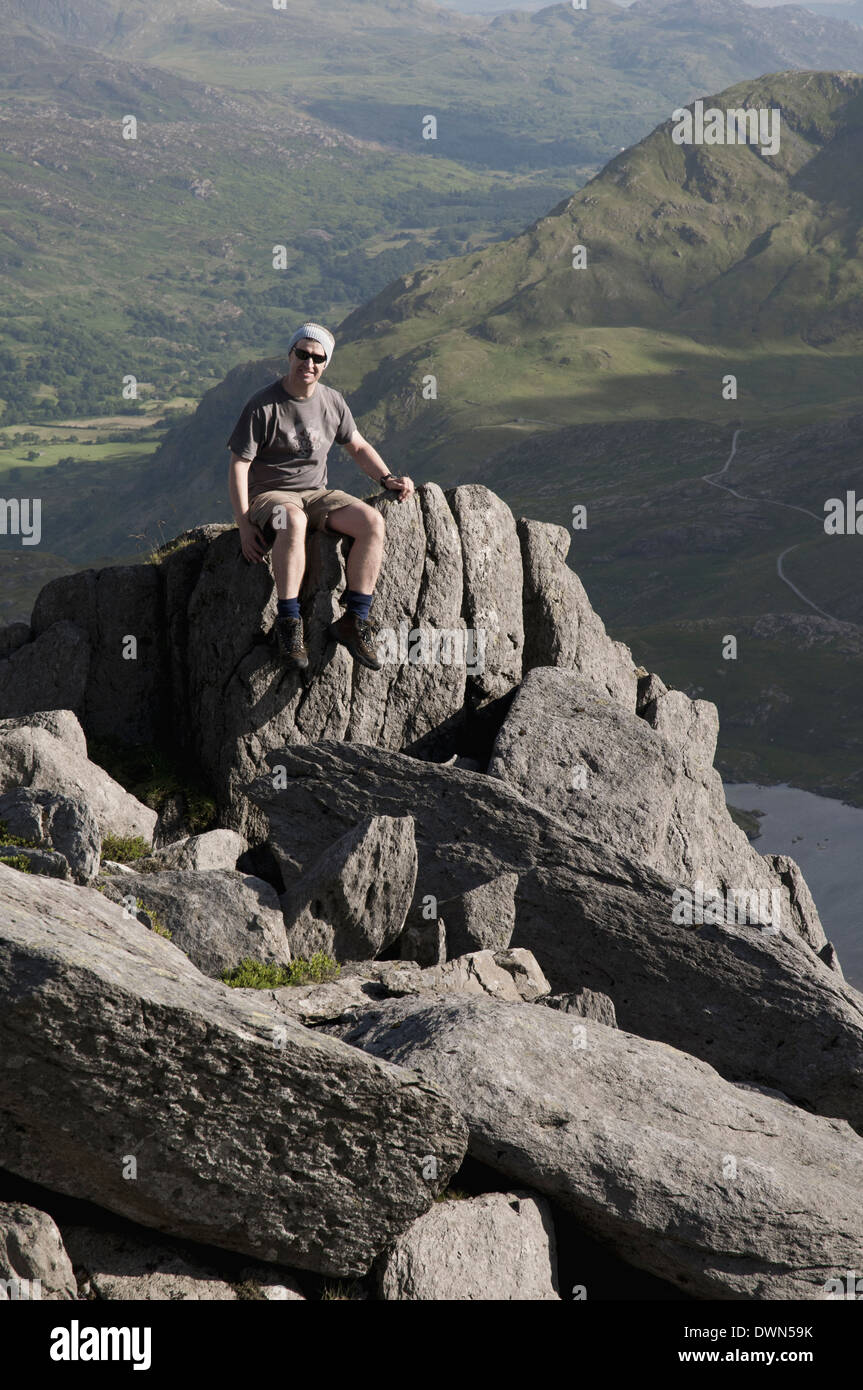 A hiker resting on a rock outcrop near Glyder Fach in the Snowdonia mountain range in Wales. Stock Photo