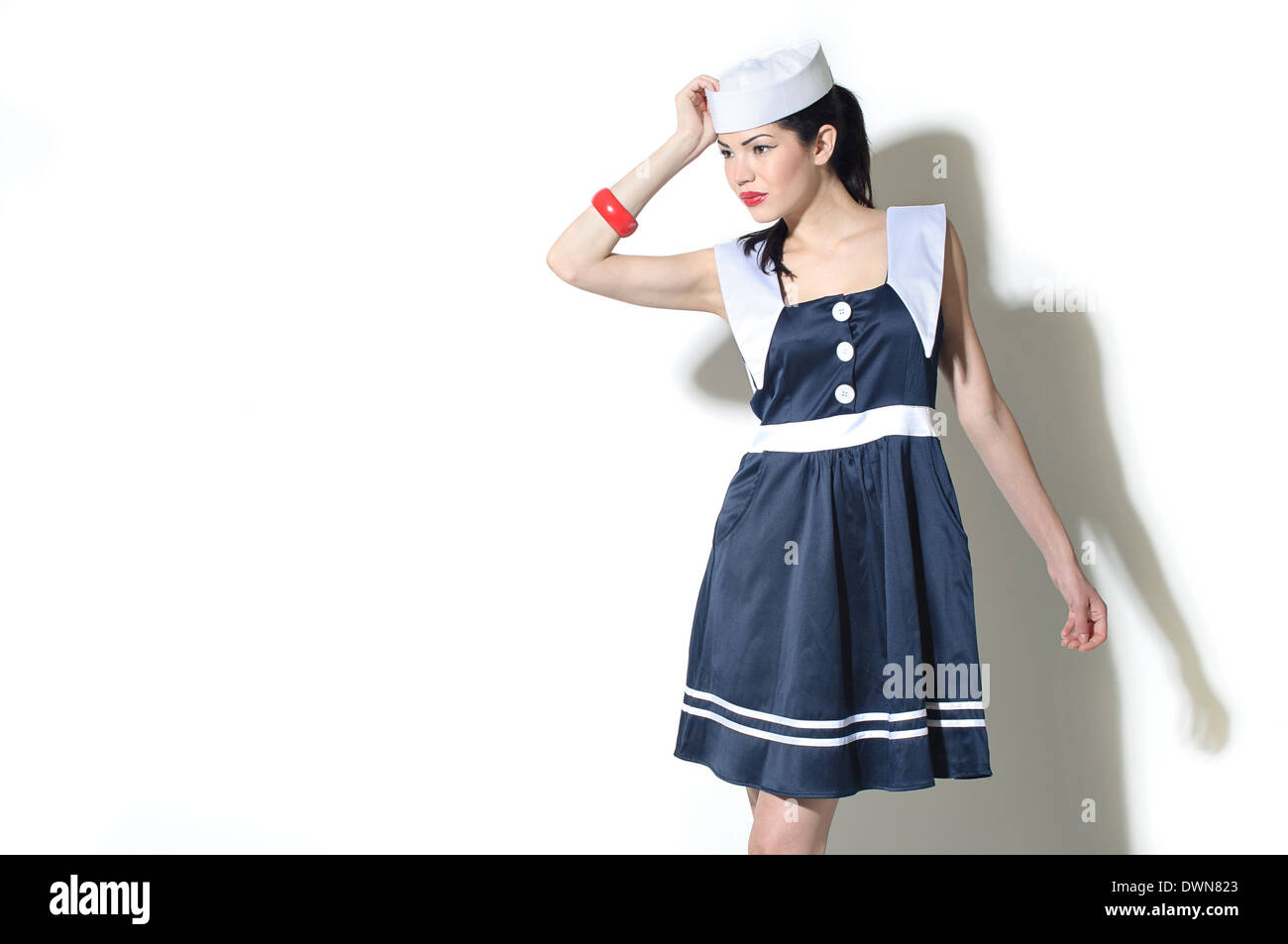 A female model dressed in a sailor dress and sailor hat posing, a retro vintage fashion concept Stock Photo