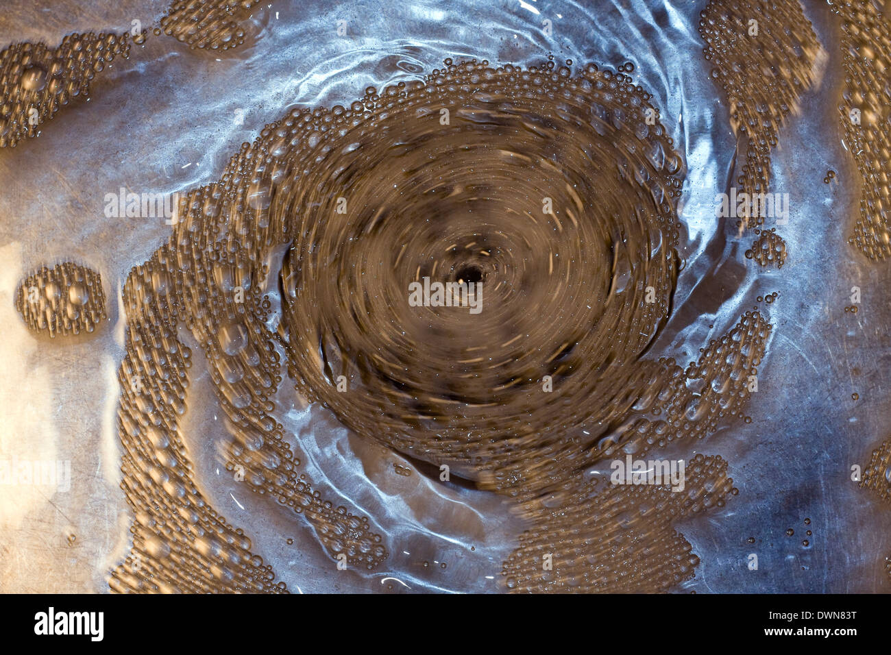 Motion Blur of bubbles spiraling in a gradually tightening circular vortex down a sink drain Stock Photo