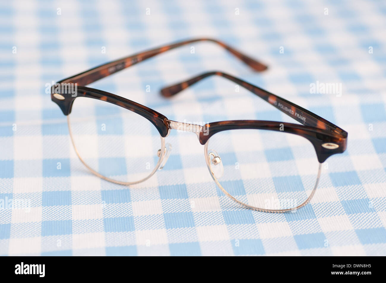 vintage 1950s style eye glasses on a blue gingham table cloth, retro accessory concept Stock Photo