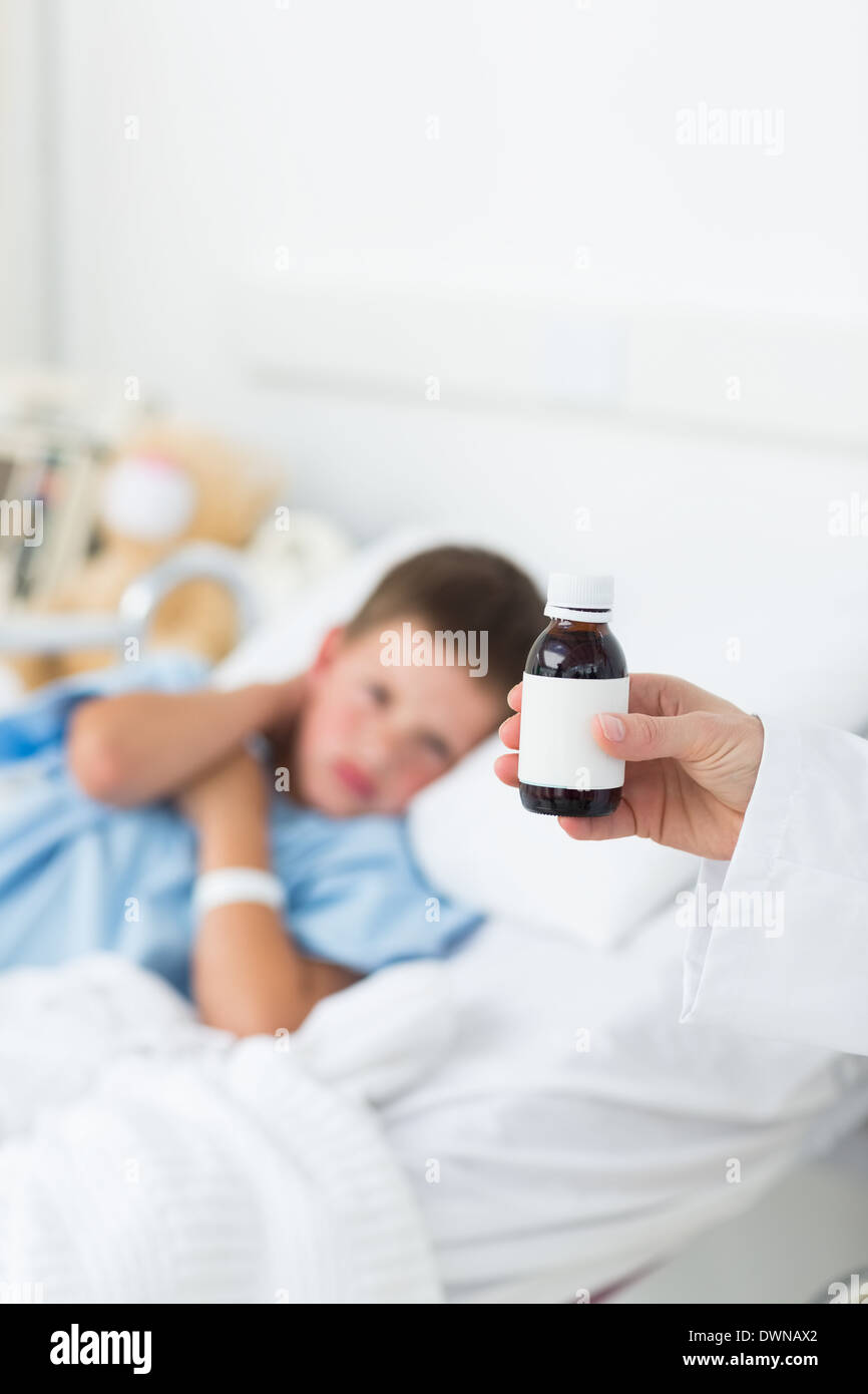 Doctor holding cough syrup with boy in hospital Stock Photo Alamy