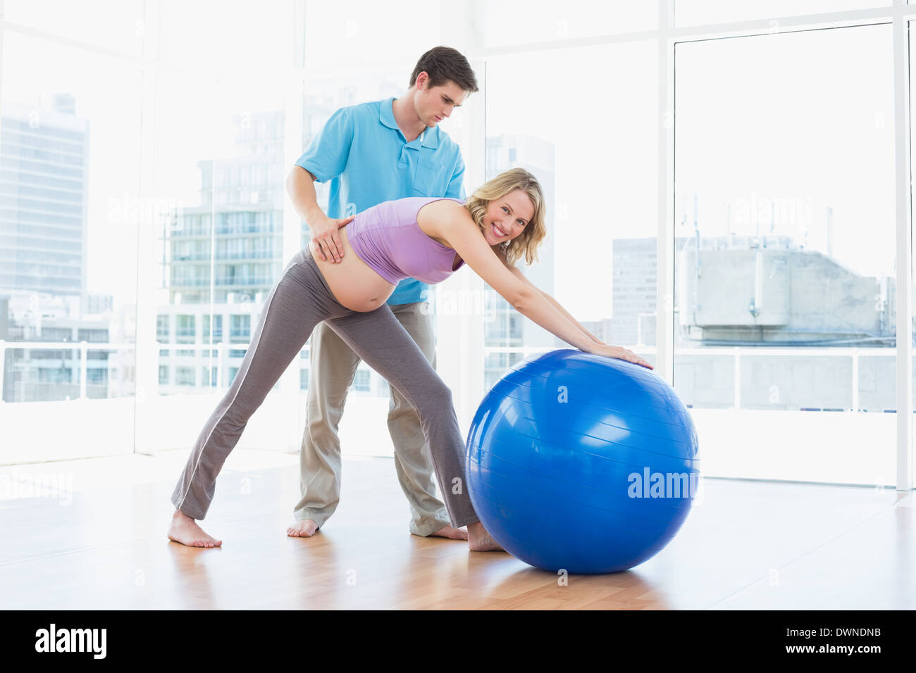 Trainer exercising with smiling pregnant client and exercise ball Stock Photo