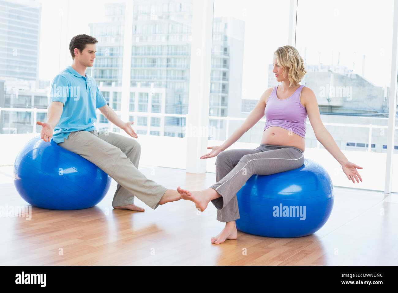 Trainer exercising with pregnant client on exercise balls Stock Photo