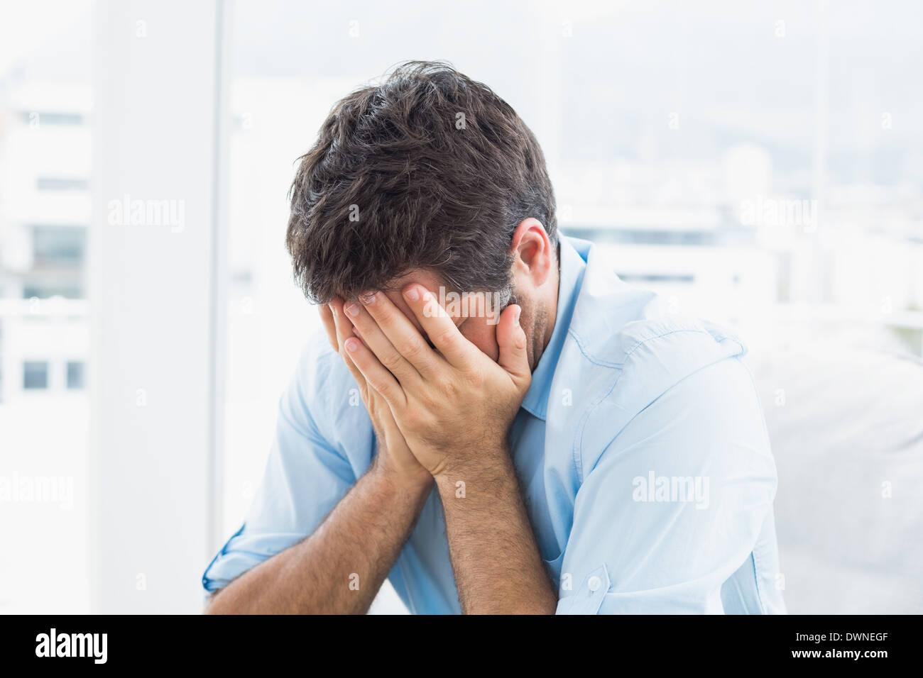 Man with head in hands sitting on the couch Stock Photo