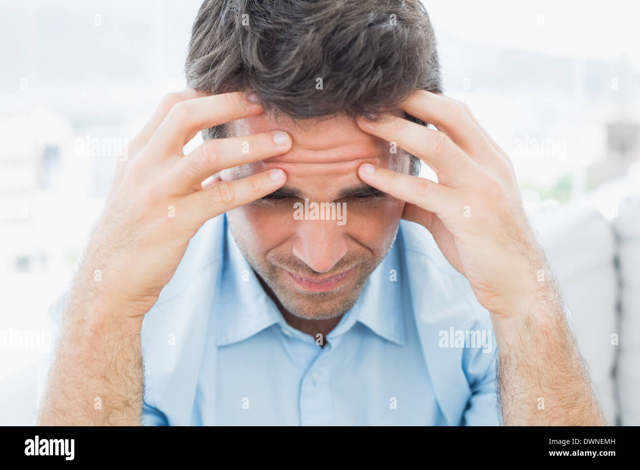 Attractive man sitting on the couch with headache Stock Photo