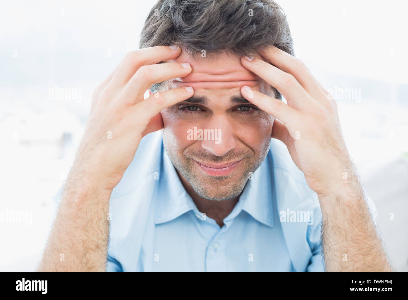 Attractive man sitting on the couch with headache looking at camera Stock Photo