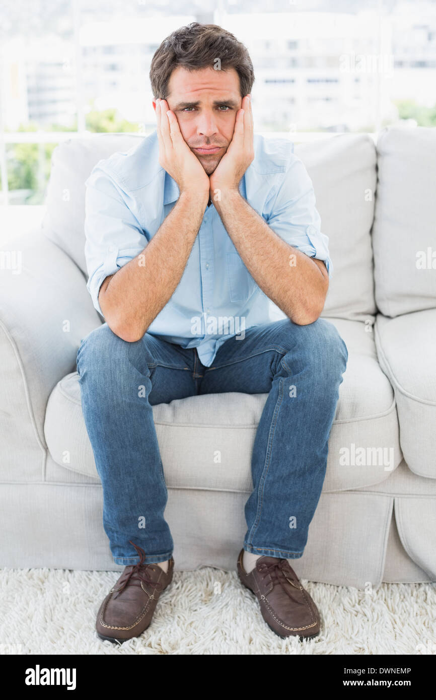 Upset man sitting on the couch looking at camera Stock Photo