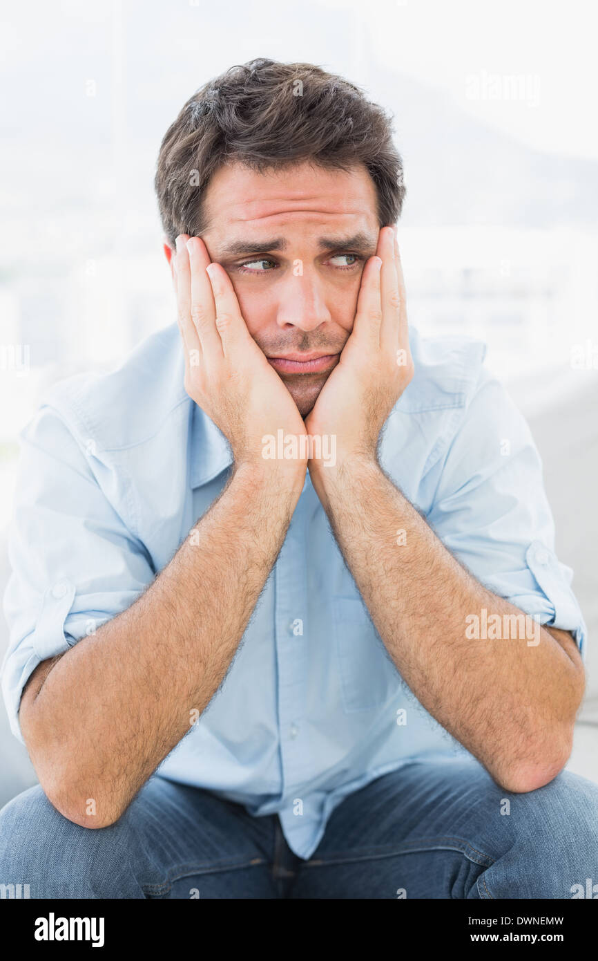 Sad man sitting on the couch looking away Stock Photo