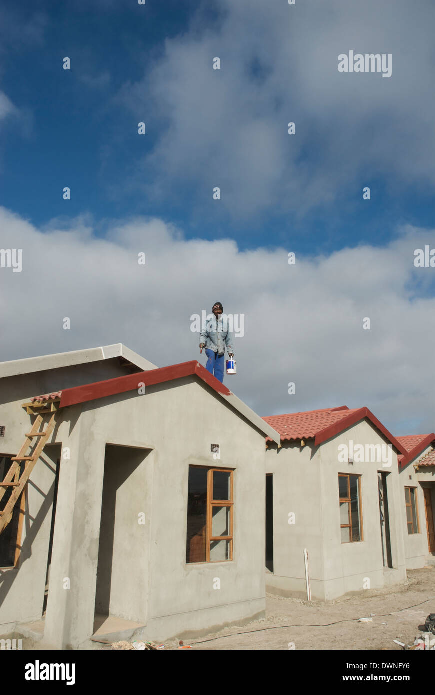 A labourer paints the roof of a new house, Atlantis, Western Cape