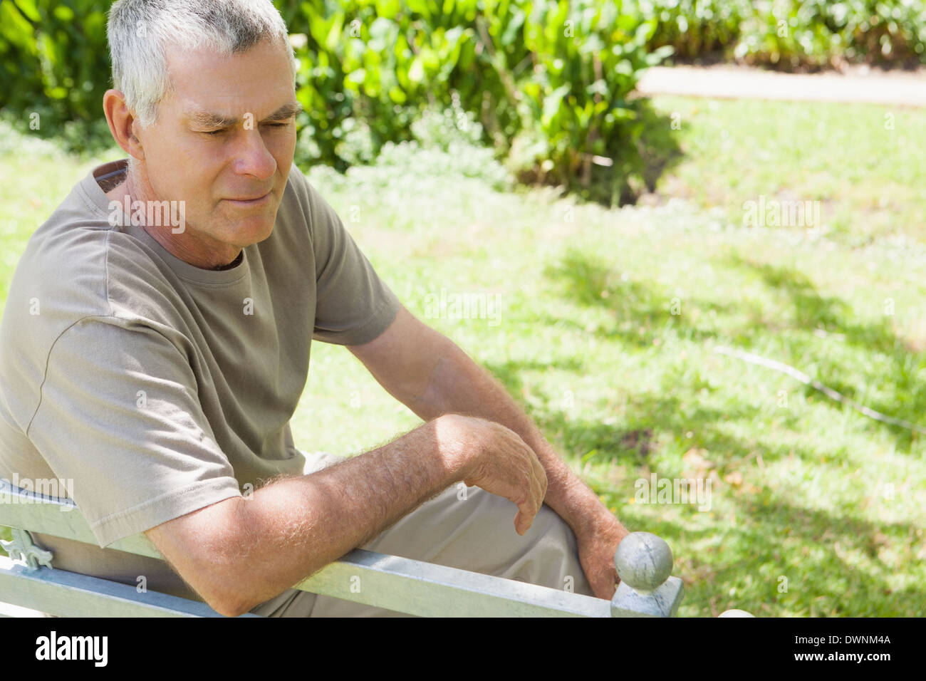 Thoughtful mature man sitting on park bench Stock Photo - Alamy